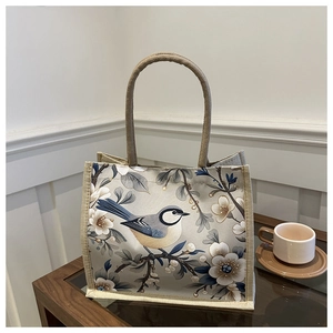 Detailed view of beige linen tote bag with blue magpie print on a wooden table