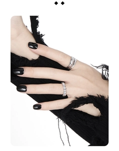 Macro shot of silver textured lava ring and square zircon band on a black knit fabric