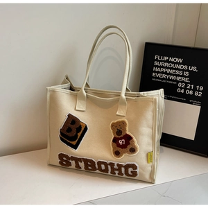 Detail of plush teddy bear applique and letter B embroidery on canvas tote bag