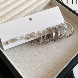 Close-up of 6 pairs of silver heart studs and hoop earrings set on white display card