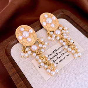 Close-up of vintage oval pearl tassel earrings with gold finish on linen background