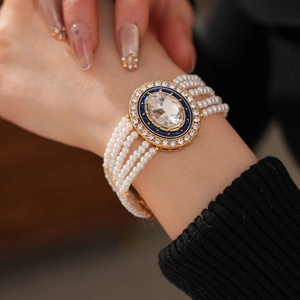 Detail of multi-layer pearl bracelet with blue enamel and crystal centerpiece on wrist
