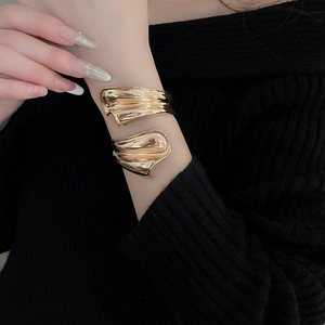 Nahaufnahme des goldglänzenden Armreifs mit unregelmäßigem Wellen-Design