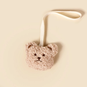 Détail de l'attache-tétine ours en peluche marron doux avec texture gaufrée et cordon blanc
