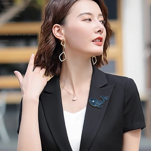 Gros plan d'une broche baleine bleue sertie de cristaux sur un blazer de costume noir