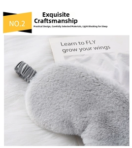 Close-up of grey plush sleep mask with satin elastic strap on soft fur background