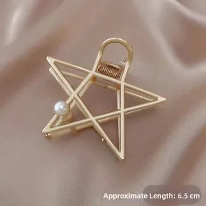 Detail of a 6.5cm gold star hair claw clip with a single white pearl on champagne silk