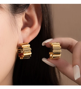 Macro shot of gold tiered striped C-shape hoop earring showing geometric layered structure