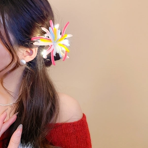 Detail view of a colorful LED pipe cleaner hair clip with fireworks design on model