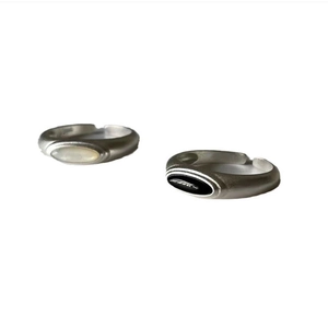 Detail of matte silver rings with white shell and black agate insets on white background