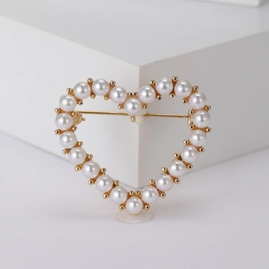 Elegant hollow heart brooch with white pearls and gold metal frame on a white display