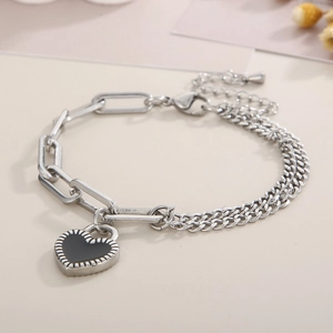 Detail of silver dual-chain bracelet with black heart pendant and paperclip links