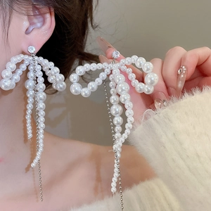 Close-up of elegant pearl bow tassel earrings on model showing delicate silver finish
