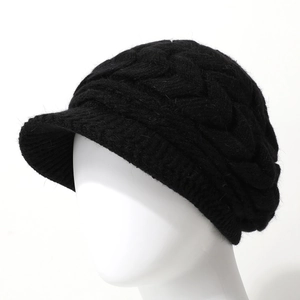 Close-up of black knitted beanie showing thick cable knit texture and sun visor detail