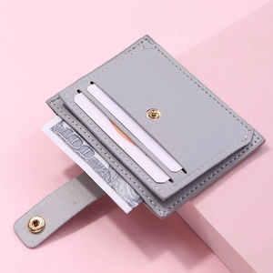 Close-up of slim grey leather card holder with gold buckle holding cards and cash