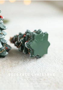 Macro detail of mini resin Christmas tree with red baubles, gold chains, and snowy accents