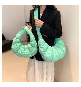 Detail of mint green quilted dumpling bag showing pleated texture and crossbody style