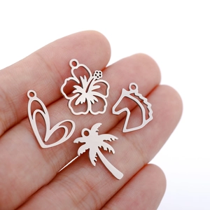 Silver stainless steel heart, flower, horse and palm tree pendants displayed on palm