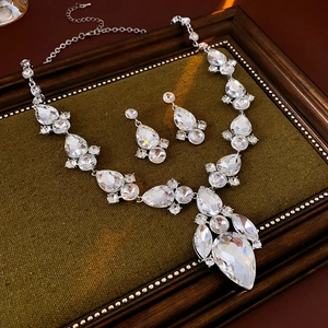 Dettaglio del set collana e orecchini con pendente a goccia e strass su velluto verde