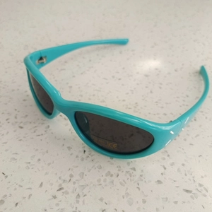 Detail view of cyan sunglasses with UV400 and CE certification on dark lenses