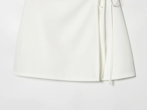 Detail of white wrap dress featuring fine side-tie design and premium woven fabric texture