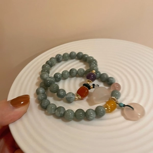 Detail of jade chalcedony beaded bracelet with colorful charms and pink donut pendant