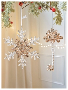 Macro view of clear acrylic snowflake and key ornaments with glittering gold sequins