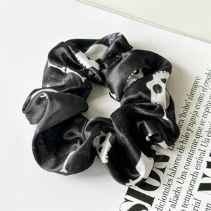 Detail of black satin scrunchie with white skull and bone patterns for Halloween fashion