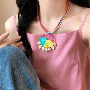 Close-up detail of a colorful round raffia and shell necklace for bohemian resort style
