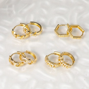 Detailed view of four pairs of gold zircon butterfly stud earrings with star and link designs
