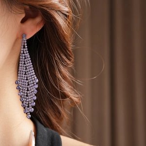 Gros plan de boucles d'oreilles à longs glands violets et strass portées par un mannequin