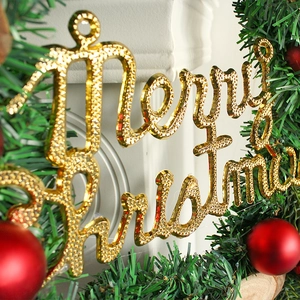 Goldener Glitzer Merry Christmas Schriftzug auf grünen Tannenzweigen mit roten Kugeln