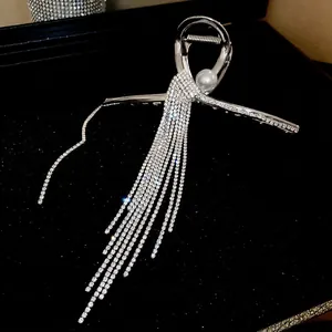 Pince à cheveux argentée avec perle et longs glands en strass sur fond noir élégant