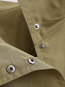 Detailed macro view of olive green bomber jacket featuring metallic snap buttons and twill fabric