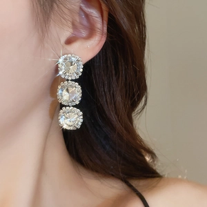 Close-up of elegant silver long drop earrings with three sparkling round crystal elements