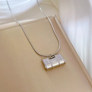 Detailed close-up of a silver Fu character lock pendant on a sleek snake chain necklace