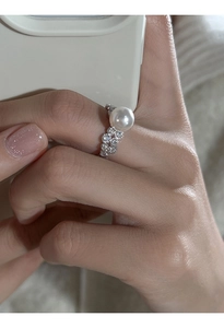 Close-up of a silver lace ring featuring a white pearl and sparkling rhinestones