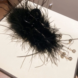 Detail of black feather hair claw clip with sparkling rhinestone fringe and grey beads