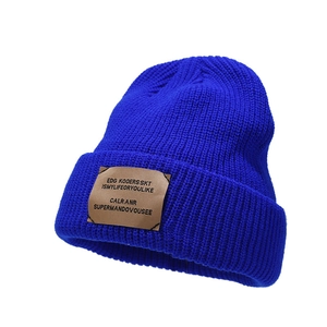 Blue ribbed knit beanie with a brown leather patch for autumn and winter warmth