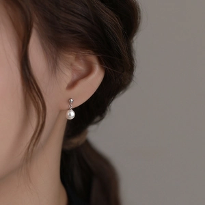 Elegant S925 sterling silver pearl drop earrings worn by a model in a minimal style
