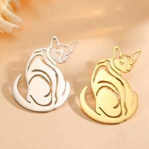 Cat-shaped hollow titanium steel brooches in gold and silver finish on a warm background