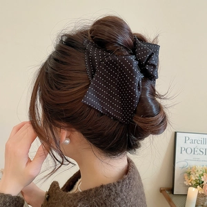 Detailed view of back-worn black polka dot bow hair claw clip on brunette hair
