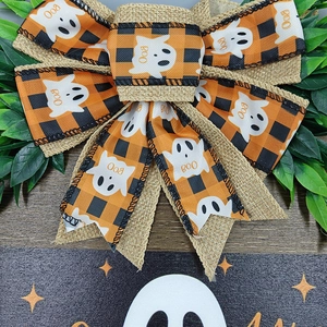 Detail of Halloween bow with orange black plaid ribbons and ghost patterns on wood sign