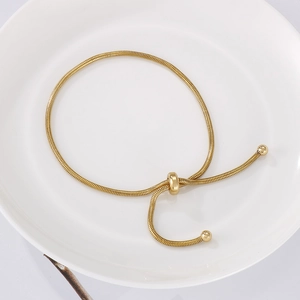 Close-up of golden adjustable snake chain bracelet on white plate with slide clasp
