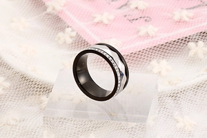 Close-up of a wide stainless steel ring with black and silver bands and pavé diamonds