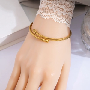 Detailed view of women's gold cable twisted cuff bracelet in a lifestyle setting