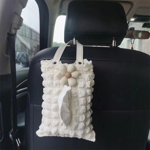 Detail of cream white bubble fabric car tissue holder hanging on back of vehicle seat