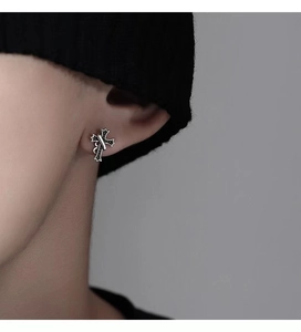 Close-up of 925 sterling silver cross earring for men with black textured details