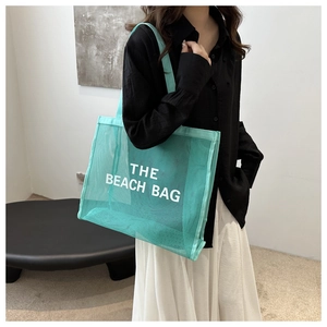 Detail of mint green mesh beach bag with The Beach Bag text print in summer style