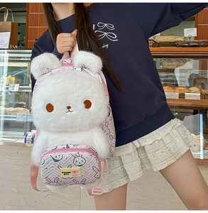 Detail of white plush rabbit backpack with pink shoulder straps and bunny pattern pocket
